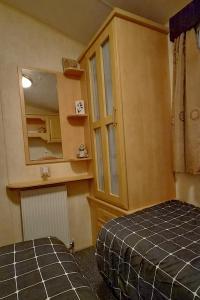a bedroom with a bed and a cabinet and a mirror at MOLLIES DEN 2 8 Berth 3 Bedrooms The Grange Holiday Park INGOLDMELLS in Ingoldmells