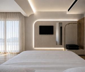 a bedroom with a white bed and a flat screen tv at Harmony Hotel Nafplio in Nafplio