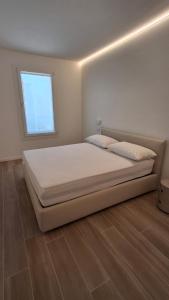 a bedroom with a white bed with a window at VELORA STAYS Florinas in Lido di Jesolo +45 photos