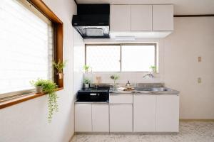 a kitchen with white cabinets and a sink and a window at Quiet Myoden-Disney & Tokyo Sightseeing Base in Ichikawa