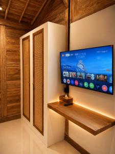 a flat screen tv on a wall in a room at Joglo Ulu Home in Uluwatu