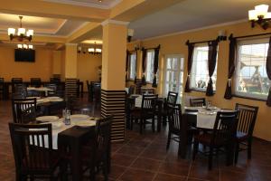 Gyongyvirag Panzio (Pensiunea Lacramioara) في Turia: غرفة طعام مع طاولات وكراسي ونوافذ