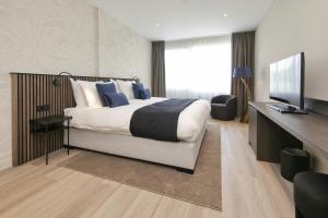 a bedroom with a large bed and a television at Boutique Hotel Hans - Amsterdam Schiphol Airport in Badhoevedorp