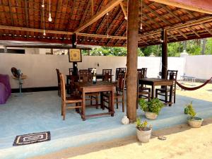 a restaurant with wooden tables and chairs under a pavilion at Summer wave kudawa and Kite surfing school in Kalpitiya