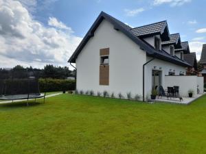 a white house with a green lawn at Apartamenty Babie Lato in Białogóra