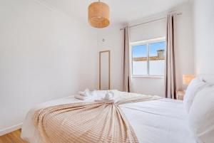 a white bedroom with a bed with a large window at Albufeira prime stay in Albufeira