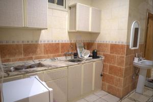 a tiled kitchen with a sink and a toilet at كيان الين الشبلان - KAYAN ALYN AlMansak Suites in Abha