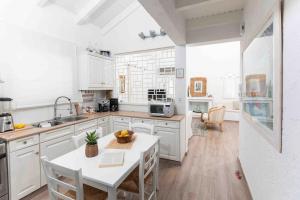 a kitchen with white cabinets and a white table at Villa NS in Perdika
