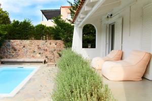 a patio with two leather chairs and a swimming pool at Villa NS in Perdika