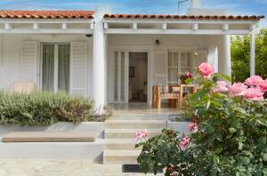 a white house with a patio with pink roses at Villa NS in Perdika