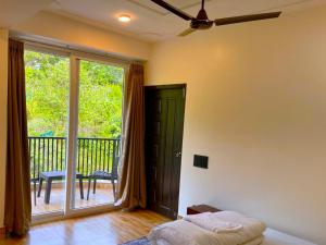 a bedroom with a bed and a balcony with a sliding glass door at Happy Homestay Sittong in Mangpu