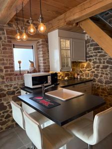 a kitchen with a counter with a sink and chairs at Le Menes in Andenne +9 photos
