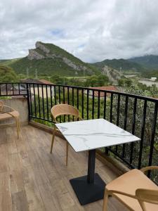 a white table and chairs on a balcony with mountains at Bujtina Lugina e vjosës in Përmet