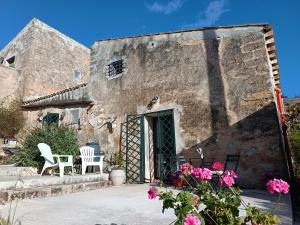 an old stone building with two chairs and flowers at Agri Experience - Case Gentile in Castelvetrano Selinunte