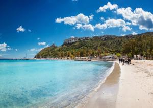 a beach with blue water and a mountain in the background at L'Antica Torre Caralis Holiday in Cagliari