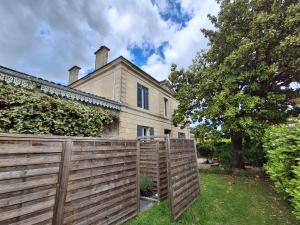a house with a wooden fence in front of it at L'entre deux M in Saint-Loubès