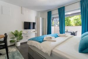 a bedroom with a large bed with blue curtains and a window at Holiday Apartments Amarilis in Pakoštane +132 photos