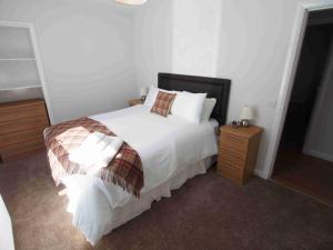 a bedroom with a white bed and a wooden night stand at APL Apartments in Aberdeen