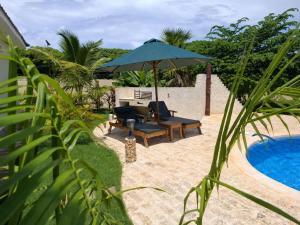 a patio with a chair and an umbrella next to a pool at Ferienhaus Vacation Villa Diani Beach in Kinondo