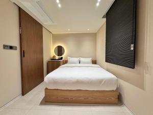 a bedroom with a large bed with white sheets at The hotel 1997 - 더호텔 1997 in Seoul