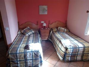 2 camas en una habitación con paredes rojas en Casa Rural Pastora Marcela, en Saceruela