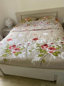 a white bed with a floral comforter on it at Les clés du temps in Essarts