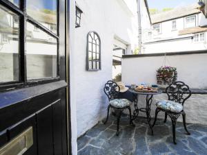 a patio with chairs and a table on a balcony at Miranda Cottage in Polperro