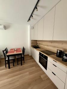 a kitchen with white cabinets and a table with chairs at Justinrent PALATIUM 31 in Legnica