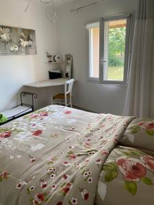 a bedroom with a bed with a floral bedspread at Les clés du temps in Essarts