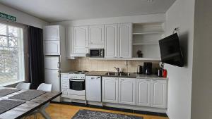 a kitchen with white cabinets and a sink and a table at Outapailakka K18 in Saariselka