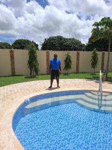 a man standing next to a swimming pool at Ferienhaus Vacation Villa Diani Beach in Kinondo