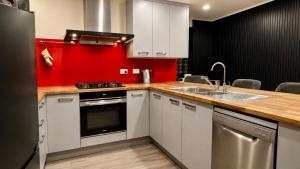 a kitchen with white cabinets and a red wall at The Crossing Lodge in National Park +133 photos