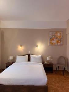 a bedroom with a large white bed with two tables and a chair at Hotel Lemnos in Myrina +46 photos
