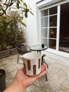 a hand holding a coffee cup in front of a patio at Andrra Apartment in Prishtinë