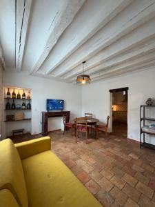 a living room with a yellow couch and a table at Maison de bourg de village in Dame-Marie-les-Bois