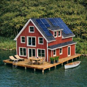 a house with solar panels on a dock in the water at Seehaeuser am Lindenhof in Lychen +10 photos