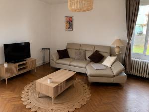 a living room with a couch and a tv at Entre Rails & Rives in Montbard