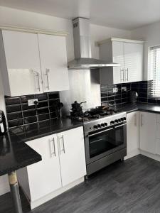 a kitchen with white cabinets and a stove at Stylish 4BR Home - Sleeps 7 - Parking & WiFi in Nottingham