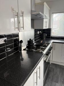a kitchen with white cabinets and black counter tops at Stylish 4BR Home - Sleeps 7 - Parking & WiFi in Nottingham
