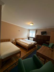 a room with two beds and a table and chairs at Gasthaus Goldener Anker in Gemünden