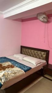 a bed in a room with a pink wall at BS Residency in Dehradun