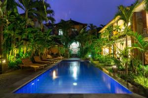 a swimming pool in a house with palm trees at Krisna House in Ubud