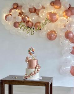 a balloon wall with a cake and a balloon garland at Seawind in Kannur