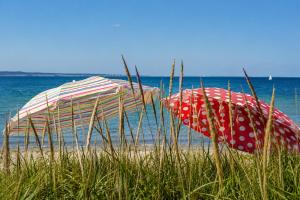 two umbrellas sitting on a beach near the water at Glaeßer Appartements in Burg auf Fehmarn +14 photos