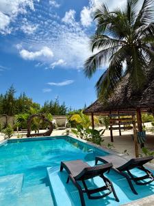 a swimming pool with two chairs and a palm tree at Pamoja Villas in Migogoni