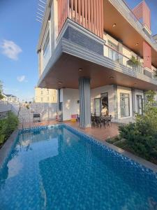 a swimming pool in front of a house at Arden Reserve Villa in Binh Thai