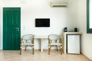 two chairs and a table in a room with a tv at Epic View Suites in Akrotiri