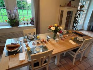 a wooden table with food and flowers on it at La Gentilhommière in Rogerville
