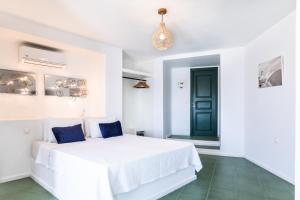 a white bedroom with a white bed with blue pillows at Epic View Suites in Akrotiri +61 photos