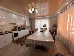 a kitchen with a table and chairs and a kitchen with white cabinets at AJO Guesthouse in Naryn